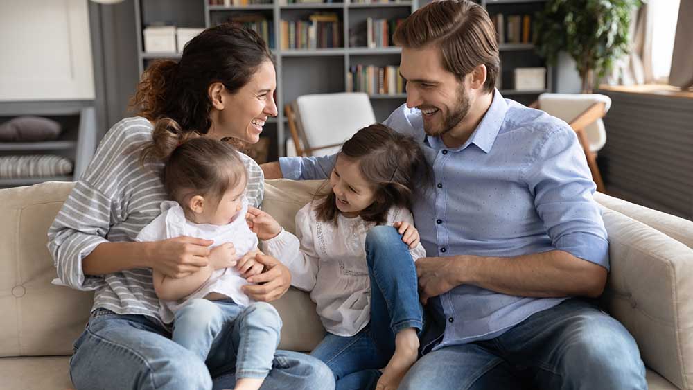 Happy young family with two kids having fun in living room